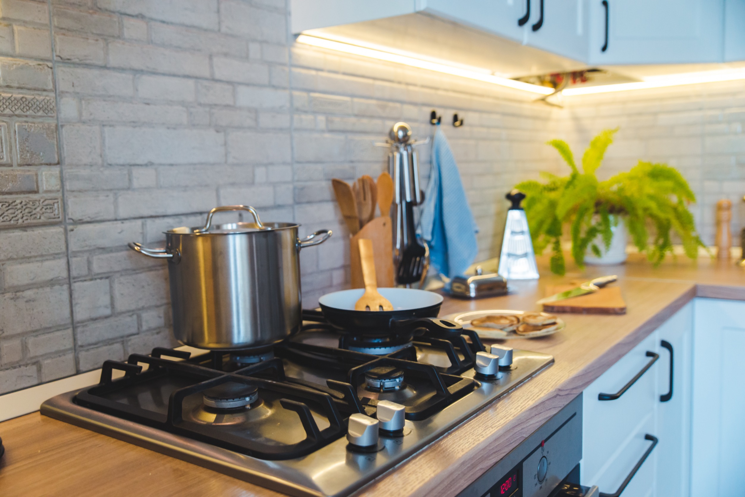 pan on stove with pancakes with countertop and backsplash visible